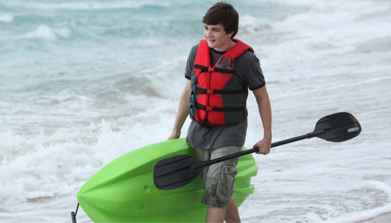 a teen carrying a kayak for kids with green bottom