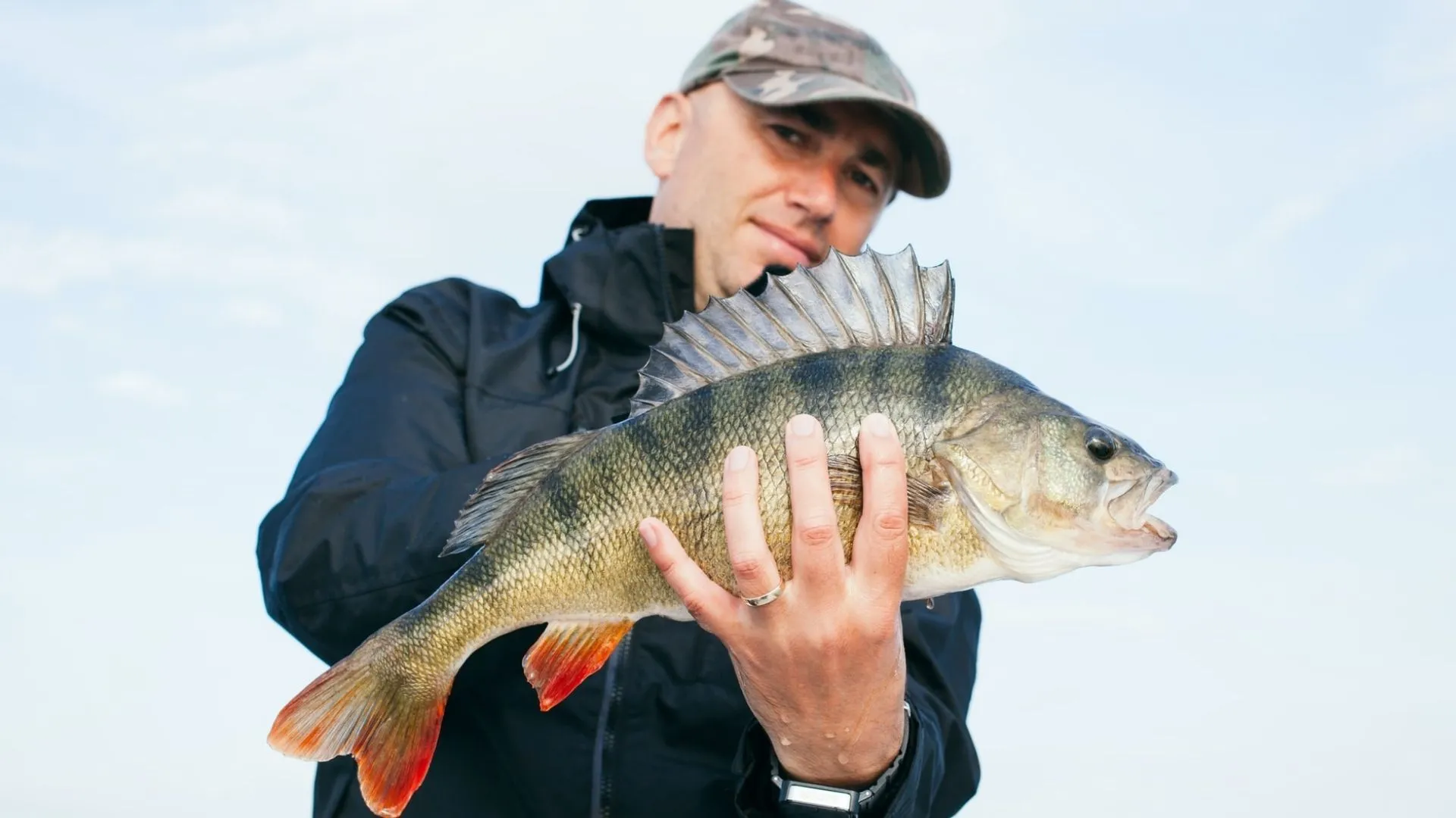 a man wearing a fishing hat holding a fish