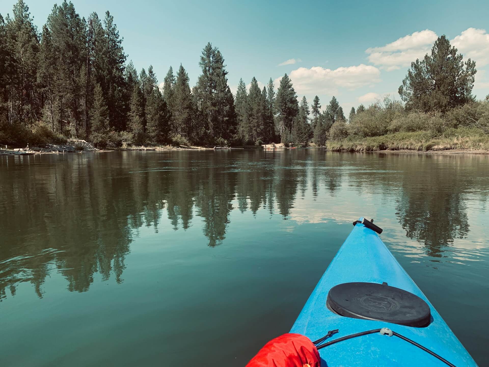 Kayaker paddling on peaceful water with light kayaking gear